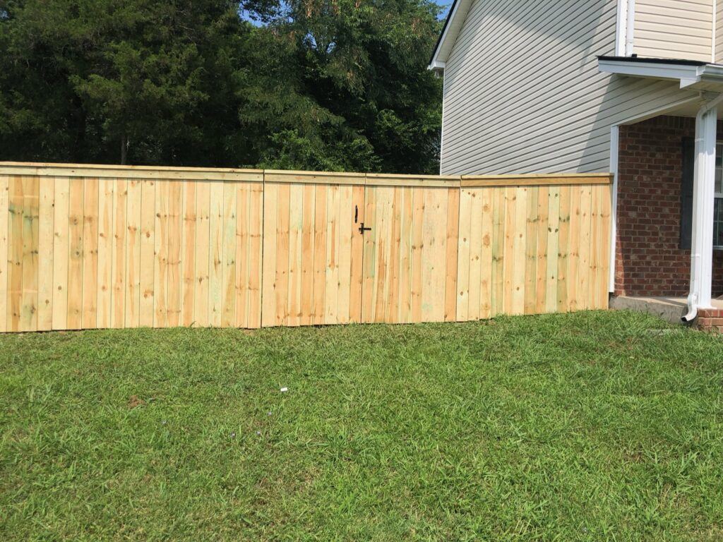 Wooden fence beside house on grass lawn.