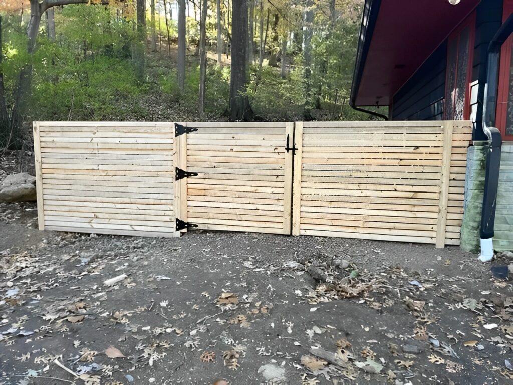 Wooden privacy fence beside a forest cabin.