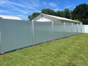 White fence with green grass and sky.