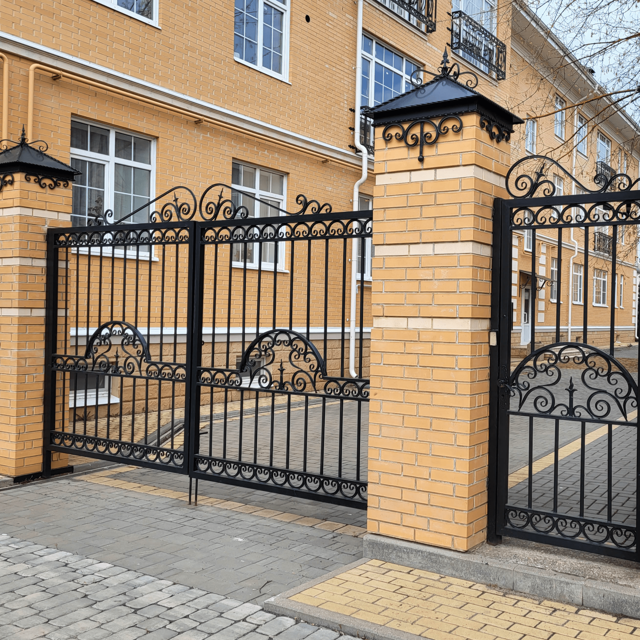 Ornate black gate and brick building exterior.