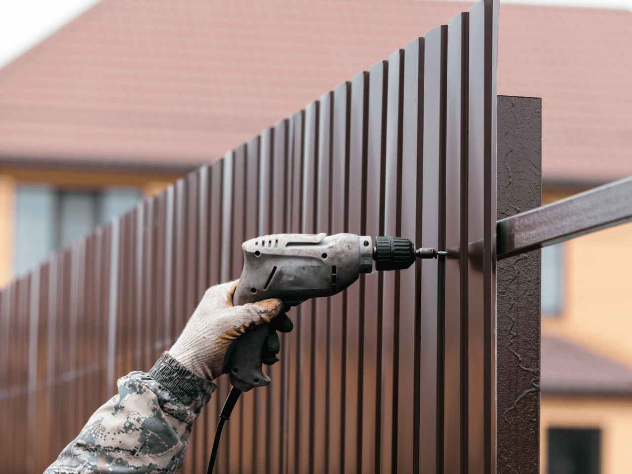 Frame 2095584586 Person drilling metal fence with power tool.