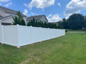 White fence beside suburban house and trees.